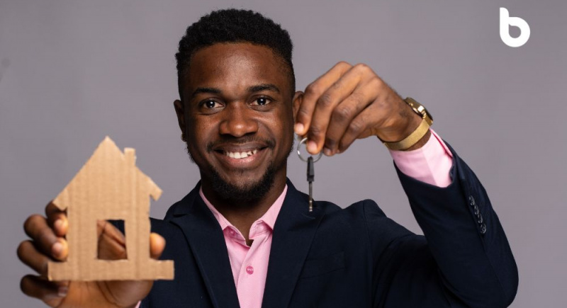 Close-up shot of an African man holding up a house key to the camera, happy he's about to buy a house