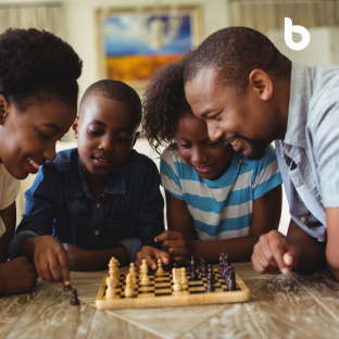 African family playing chess together, developing essential skills for smart financial decisions and echoing the focus of the article "Teach your child about money"
