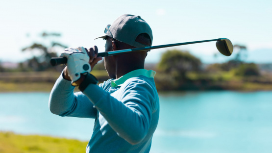 A golfer taking a tee shot on the golf course, illustrating the "playing the long game in investing" approach of setting up for future success with each action.