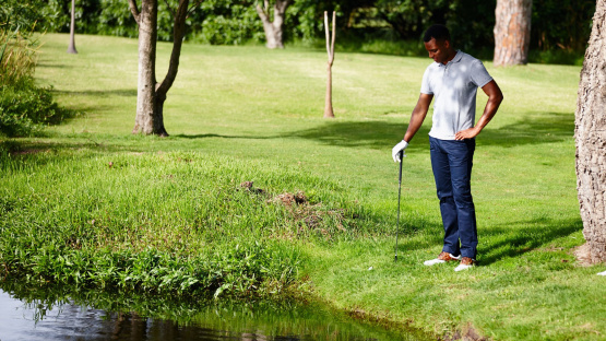 A golfer carefully navigating a hazard on the golf course, demonstrating the patience and discipline required when "playing the long game in investing" and weathering market volatility.