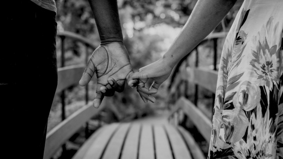 Close-up of a couple's intertwined hands with wedding rings, symbolizing their journey of choosing love over tradition despite cultural barriers